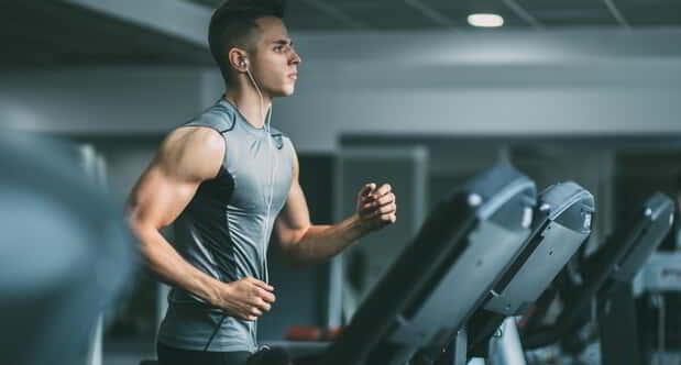 Young man in sportswear running on treadmill at gym.